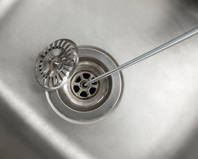 Total Repair Pros plumber operating a cable drain snake at a residential kitchen sink in South Florida